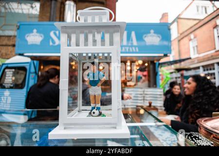 London, Großbritannien. 31. Oktober 2024. Eine Figur von Diego Maradona in den Farben der Napoli-Fußballmannschaft ist vor einem Pop-up-Stand abgebildet, in dem auf dem Spitalfields Market holzbefeuerte neapolitanische Pizzen verkauft werden. Der Stand ist besonders bekannt für seine beliebte Pizza, ein Portafoglio, oder gefaltete Brieftaschen-Pizza. Quelle: Mark Kerrison/Alamy Live News Stockfoto