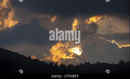 Sonnenuntergang mit stürmischem Wolkenhimmel und versteckter Sonne hinter den Wolken auf den Bergen. Troodos Zypern Stockfoto