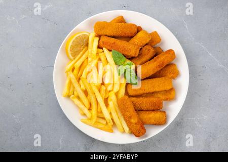 Fish and Chips. Nahaufnahme von knusprigen panierten, frittierten Fischfingern mit Brotkrumen, serviert mit Remoulade-Sauce und Zitrone Stockfoto