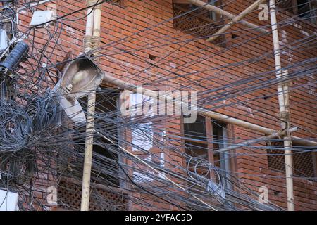 Chaotisch verwickelte Elektrizität und Telekommunikationsleitungen, Kabel auf Masten in einem Gebäude Stockfoto