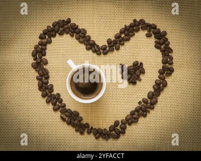 Kaffeebohnen in Form eines Herzsymbols und eine Tasse schwarzen Espresso. Konzept von I love Coffee Stockfoto