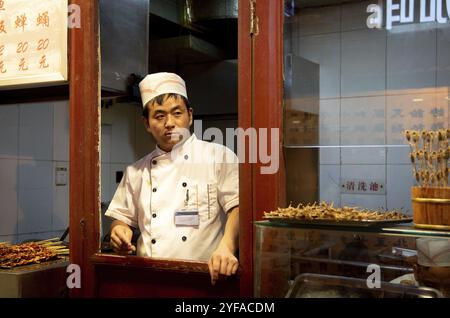 Peking, China ? 1. Juni 2018: Koch in seiner weißen Uniform kocht traditionelle chinesische Gerichte auf einem Snack Street Food Markt in Peking in China Stockfoto