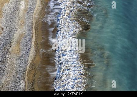 Aus der Vogelperspektive auf stürmische Meereswellen, die an einem Sandstrand brechen. Naturhintergrund Stockfoto