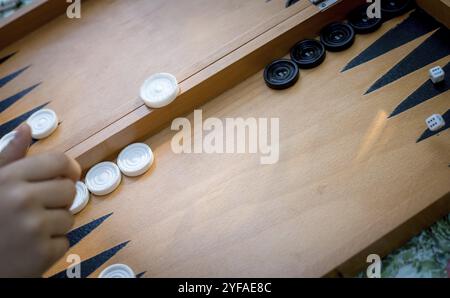 Mit der Hand würfeln Sie auf ein hölzernes Backgammon-Brett und spielen Backgammon-Spiel Stockfoto