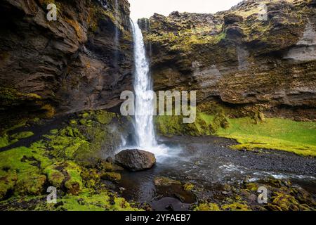 Kvernufoss Wasserfall in Island, mit einer malerischen Landschaft mit üppigem Grün, zerklüfteten Klippen, einem gewundenen Pfad und einem kaskadierenden Wasserfall Stockfoto