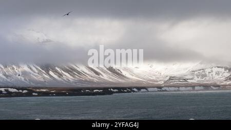 Verschneite Berglandschaft mit Wolkenlandschaft und Atlantik bei Snaefellsnes Halbinsel im Frühjahr in Island Stockfoto