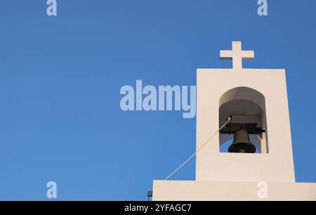 Weißer christlicher Glockenturm mit orthodoxem Kreuz auf einer griechischen Kirche gegen blauen Himmel. Religions- und Religionstempel Stockfoto