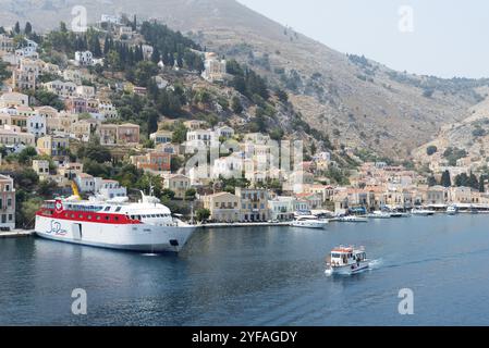 Symi, Griechenland, 1. August 2016: Panoramaaufnahme der Stadt Symi mit dem Hafen und den bunten Häusern auf dem Hügel, auf der griechischen Insel Symi an der Aege Stockfoto