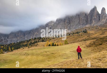 Unerkannte Person steht und genießt darin die wunderschöne nebelige Berglandschaft der malerischen Dolomiten am Sellapass in Südtirol Stockfoto