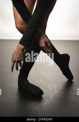 Schöne Beine von jungen Ballerina mit spitzenschuhen tanzen auf einem schwarzen Boden Hintergrund. Ballettübung. Schöne schlanke anmutige Füße des Balletttanzes Stockfoto