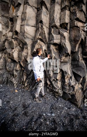 Reisende erkunden Basaltfelsen am schwarzen Sandstrand von Reynisfjara in Island Stockfoto
