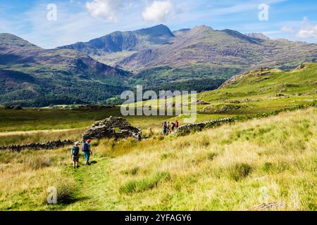 Wanderer, die einen Pfad von Cnicht hinunterlaufen, mit Blick auf Snowdon Hufeisen in den Bergen des Snowdonia Nationalparks. Beddgelert, Gwynedd, Nordwales, Großbritannien Stockfoto