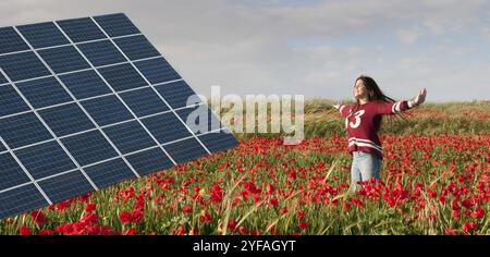 Solarenergie-Panel auf einem Feld mit roten Mohnblumen und einem Mädchen im Teenageralter, das glücklich ist, die Umwelt zu retten. Konzept der erneuerbaren Energien Stockfoto