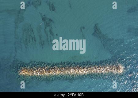 Aus der Vogelperspektive von einer fliegenden Drohne aus blauem Meerwasser und Wellenbrecher. Meeresmauer Paphos Zypern Stockfoto