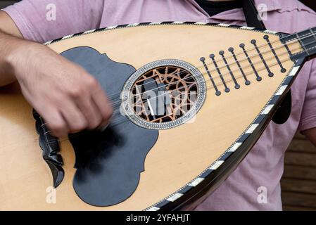 Unanerkannter Musiker, der ein traditionelles Lied mit der Laute, einem traditionellen griechischen Musikinstrument, spielt Stockfoto