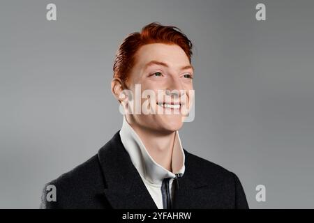 Ein selbstbewusster junger Mann mit leuchtend roten Haaren lächelt warm in einem modischen Wintermantel. Stockfoto