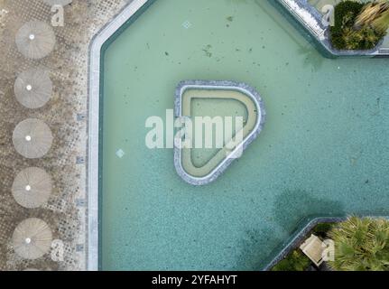 Drohnenantenne des leeren, verlassenen Hotelschwimmbades. Schmutziges Wasser verlassenes Hotel Stockfoto