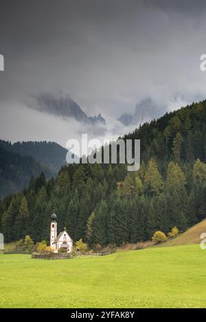 Die kleine und wunderschöne Kirche Saint John, Ranui, Chiesetta di san giovanni in Ranui Runes Südtirol Italien, umgeben von grüner Wiese, Wald an Stockfoto