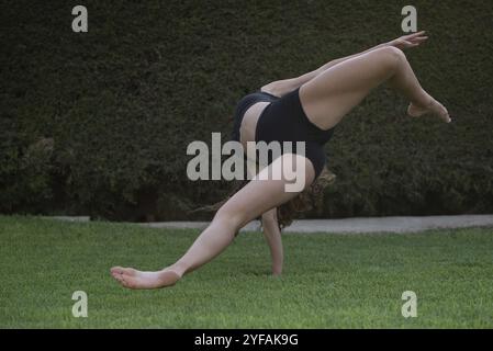 Unerkannte Frau tanzt modernen Tanz auf grünem Gras. Tanz im Freien üben Stockfoto