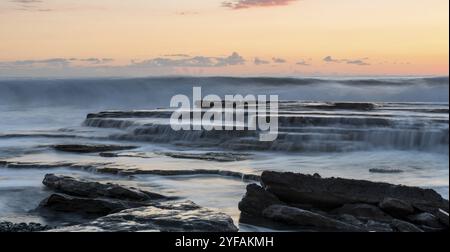 Felsigen Küste Meereslandschaft mit welligem Meer und Wellen auf die Felsen in einer dramatischen und schönen Sonnenuntergang an der Küste von Akrotiri in Limassol, Cyp Stockfoto