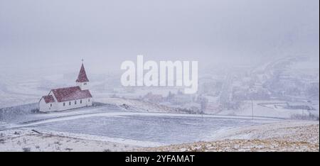 Die malerische Vik i Myrdal Kirche auf der Spitze des Hügels bei starkem Schnee im Dorf Vik in Island im Winter Stockfoto