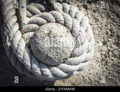 Details eines verdrehten Schiffes, das ein starkes Seil auf einem Schiffspoller zur Sicherung von Fischerbooten anlegt Stockfoto