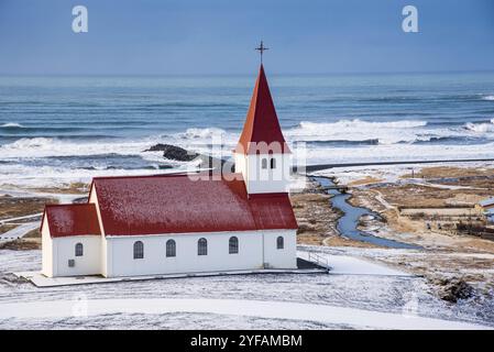 Die malerische Vik i Myrdal Kirche auf dem Gipfel des Hügels bietet malerische Bilder des atlantischen Ozeans und des Dorfes vik in Island Stockfoto