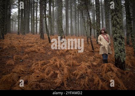 Junge Frau in Schneckenkleidung, die im Winter im Wald steht. Troodos-Gebirge Zypern Stockfoto