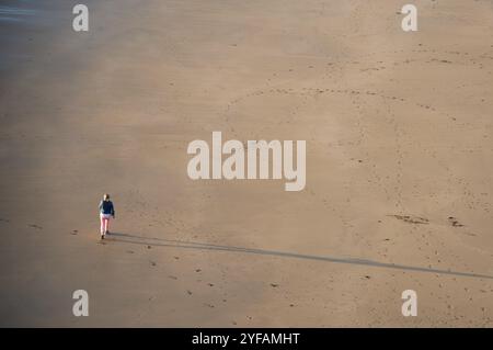 Nicht erkannte Person, die bei Sonnenuntergang am Sandstrand spaziert. Gesunder Lebensstil. Sport im Freien. Ballybunion Beach Irland Stockfoto