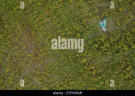 Blick auf die Frau, die auf blühendem Wiesengrasfeld liegt. Frühling im Freien Stockfoto