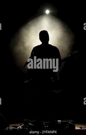 Musiker, der Gitarre spielt, spielt auf der Bühne unter Scheinwerferlicht. Silhouette eines Musikkünstlers und einer Band auf der Bühne Stockfoto