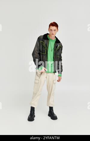 Der junge Mann mit auffälligen roten Haaren posiert selbstbewusst in einem eleganten Winteroutfit, das modernen Stil verkörpert. Stockfoto