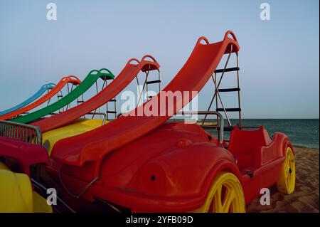 Farbenfrohe Tretboote mit Rutschen ruhen in der Abenddämmerung am Sandstrand von Albufeira Stockfoto