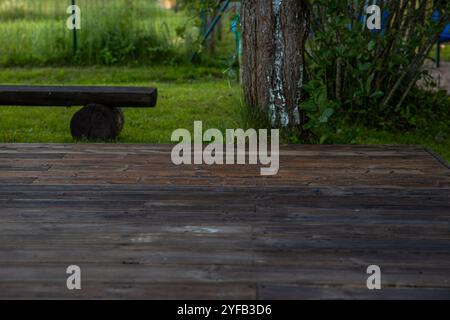 Holzterrasse mit zentralem Sandkasten im Hinterhof, umgeben von Bäumen und natürlicher Umgebung Stockfoto