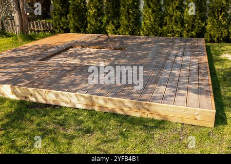 Holzterrasse mit zentralem Sandkasten im Hinterhof, umgeben von Bäumen und natürlicher Umgebung Stockfoto