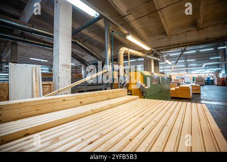 Eine große Holzbearbeitungsfabrik mit Stapeln frisch geschnittener Holzplatten, die für die Verarbeitung bereit sind und industrielle Effizienz und Präzision in einer guten Hand zeigen Stockfoto