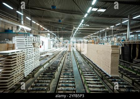 Eine große Holzbearbeitungsfabrik mit Stapeln frisch geschnittener Holzplatten, die für die Verarbeitung bereit sind und industrielle Effizienz und Präzision in einer guten Hand zeigen Stockfoto