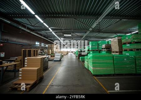 Eine große Holzbearbeitungsfabrik mit Stapeln frisch geschnittener Holzplatten, die für die Verarbeitung bereit sind und industrielle Effizienz und Präzision in einer guten Hand zeigen Stockfoto