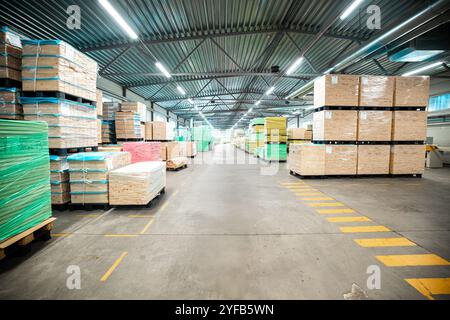 Eine große Holzbearbeitungsfabrik mit Stapeln frisch geschnittener Holzplatten, die für die Verarbeitung bereit sind und industrielle Effizienz und Präzision in einer guten Hand zeigen Stockfoto