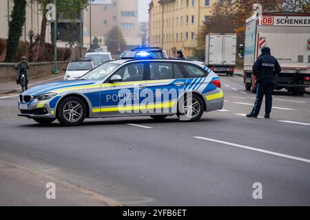 Augsburg, Bayern, Deutschland - 04. November 2024: Polizeibeamte blockieren die Straße in der Innenstadt oder errichteten mit ihrem Streifenwagen oder Polizeieinsatzfahrzeug mit blinkenden Blaulichtern und Sirene während des IG Metall-Warnstreiks auf MAN eine Straßensperre. *** Polizisten sperren Straße in der Innenstadt ab, bzw. Errichten Sie eine Straßensperre mit Ihrem Streifenwagen bzw. Einsatzfahrzeug der Polizei, mit Blaulicht und Martinshorn, beim IG Metall Warnstreik der MAN. Stockfoto