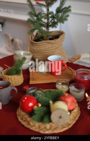 Diese zauberhafte Weihnachtskulisse fängt die Wärme und Freude der Weihnachtszeit ein. Der Tisch ist mit funkelnden Lichtern, elegantem Geschirr und saisonaler Dekoration dekoriert und bietet eine perfekte Mischung aus Tradition und Moderne. Stockfoto