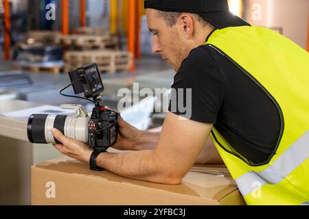 Kameramann in einer gelben Weste filmt industrielle Prozesse in einer Werkstatt und betont dabei die Aufmerksamkeit auf Details und Ausrüstung. Stockfoto