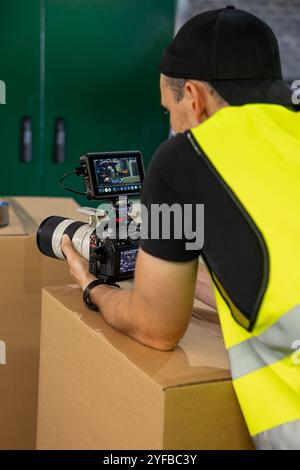 Der Kameramann in einer gelben Sicherheitsweste filmt Nahaufnahmen von Industriemaschinen und konzentriert sich dabei auf die Details der Ausrüstung. Stockfoto