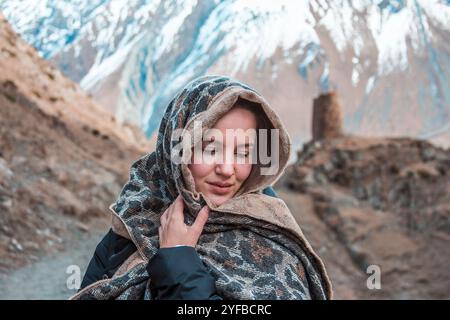 Wunderschöne Frau in Schal mit verschneiten georgianischen Bergen im Hintergrund Stockfoto