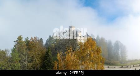 Polen. Mittelalterliche Burg in Niedzica aus dem 14. Jahrhundert (obere Burg) im Herbst im Oktober und Morgennebel. Bäume in wunderschönen Herbstfarben. Sunri Stockfoto