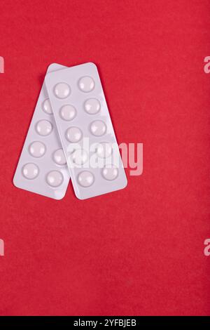 Weiße pharmazeutische Pillen in Blisterpackungen angeordnet auf lebendigem rotem Hintergrund - Medikation, Gesundheitswesen und medizinisches Behandlungskonzept Stockfoto