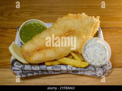 Traditionelle Fish and Chips, die in Zeitungen verpackt sind, bilden einen Chips-Shop Stockfoto