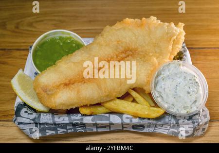 Traditionelle Fish and Chips, die in Zeitungen verpackt sind, bilden einen Chips-Shop Stockfoto