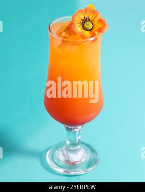 Ein farbenfroher orangener Cocktail mit Blumenapplikationen, der zitronige Süße und tropischen Charme vereint. Stockfoto