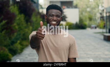 Bewegende Aufnahme ernsthafte birassische ethnische männliche Blick auf die Kamera Afroamerikaner Mann in der Stadt lächelnd glückliche Show hohe zufriedene Finger gute Geste zeigen Stockfoto